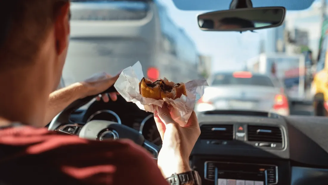 Homme qui mange au volant de sa voiture