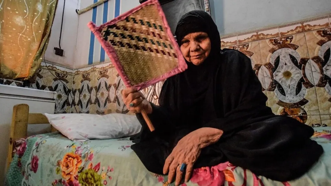 Une femme utilise un éventail a cause de la canicule