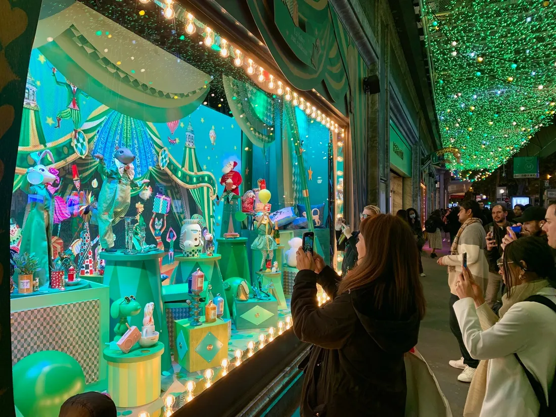 Les passants découvrent émerveillés les vitrines de Noël sur le boulevard Haussmann.