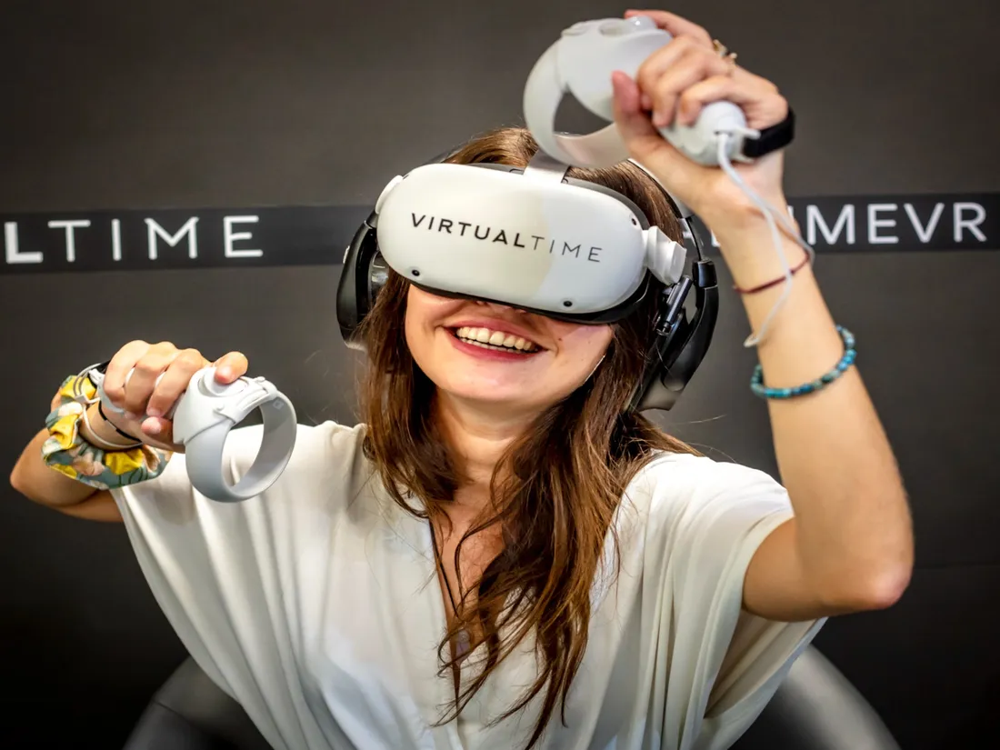 Une joueuse teste une expérience de tir à l'arc dans un box de Virtual time