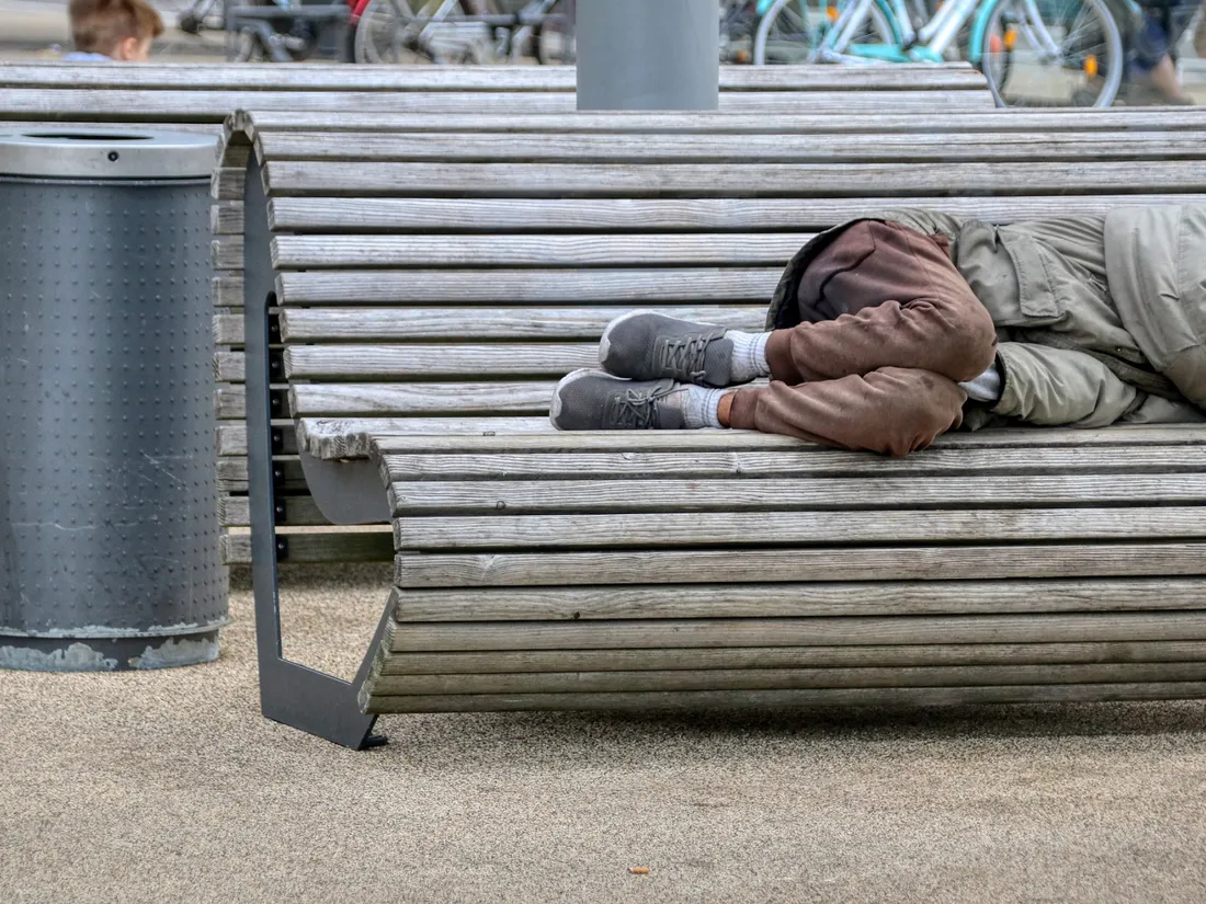 Une personne sans abri allongée sur un banc