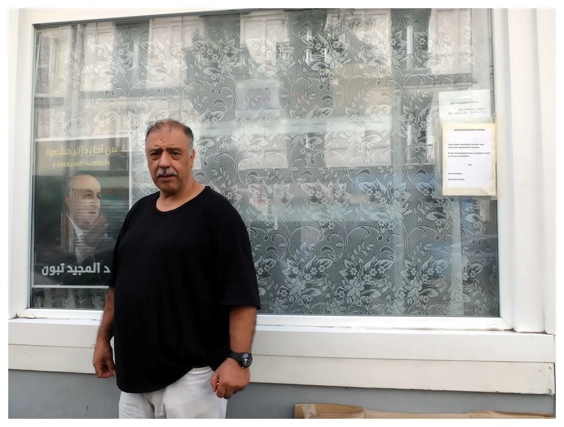 Meziane Amrane devant un portrait d'AbdelMajid Tebboune dans le quartier de la Goutte d'Or à Paris