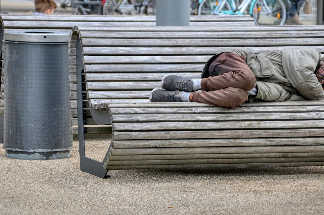Une personne sans abri allongée sur un banc
