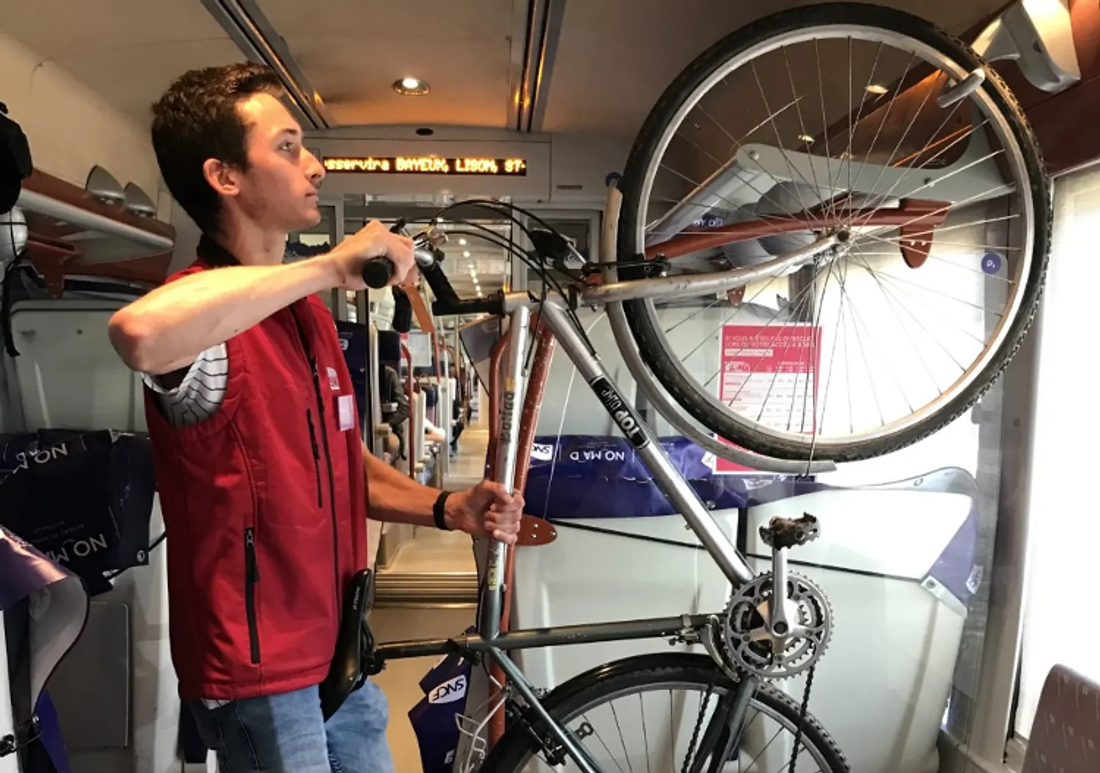 Un agent de la SNCF accroche un vélo dans le train
